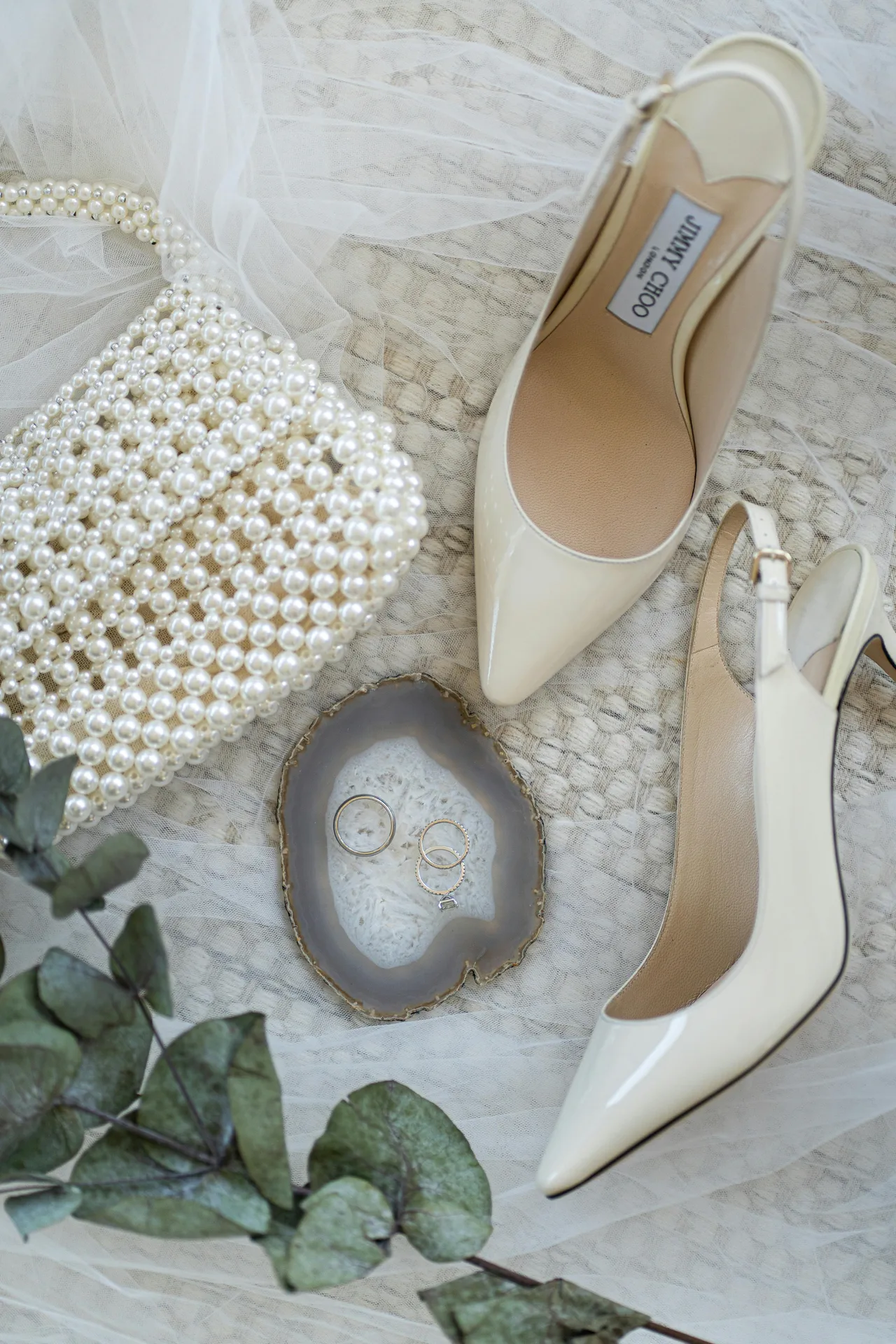 Styled Flatlay mit Absatzschuhen, Perlentasche und Eheringen
